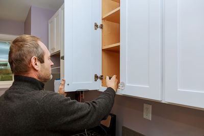 Man tightening cabinet door at home