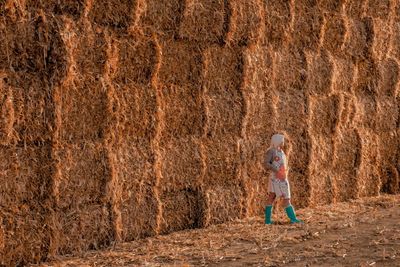 Mid adult woman standing against hay bales