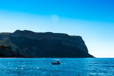 Boat sailing on sea against clear blue sky