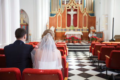 Rear view of bride and groom on seat in church