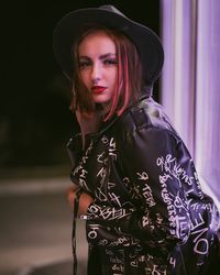 Portrait of young woman standing against window