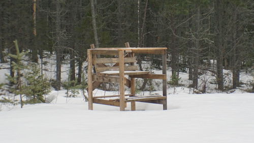 Wooden chair on snow covered field during winter