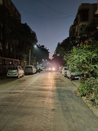 Cars on road by buildings in city against sky