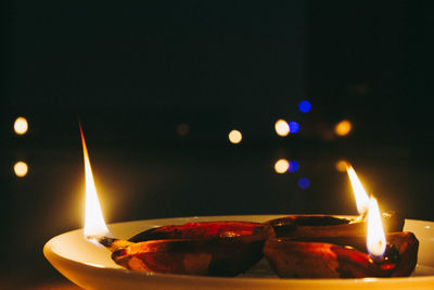 Close-up of lit candles burning at night