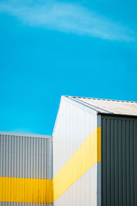 Low angle view of yellow flag on building against blue sky