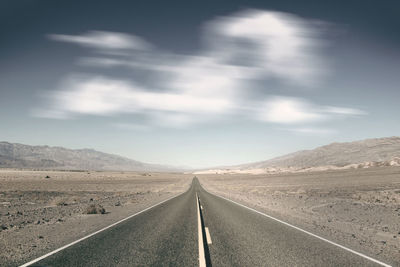 Road leading towards mountain against sky, death valley 