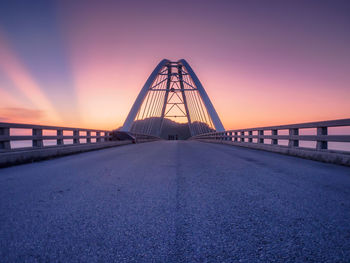 Surface level of bridge over road against sky during sunset