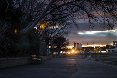 Illuminated street light in city against sky at night