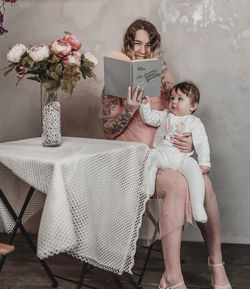 Portrait of smiling mother and daughter sitting at home