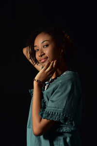 Portrait of beautiful young woman against black background