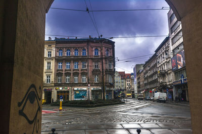 Road by buildings against sky in city