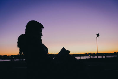 Silhouette man using smart phone against sky during sunset