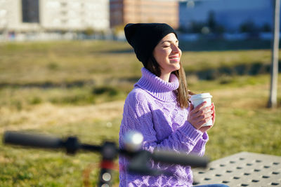 Woman holding coffee cup on field