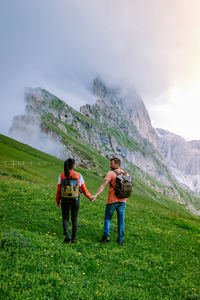 Rear view of men standing on mountain against sky