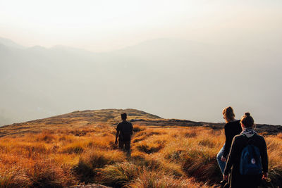 Rear view of people walking on mountain against sky