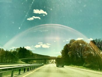 Rainbow over road against sky