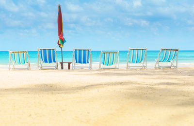 Deck chairs at beach against sky