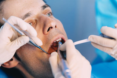 Cropped hands of dentists examining man in clinic