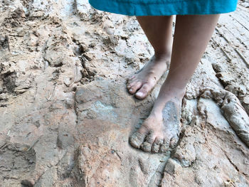 Low section of child standing in mud