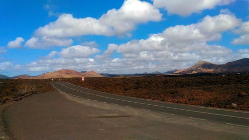 Scenic view of road by mountains against sky