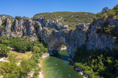 Natural arch over river against clear sky