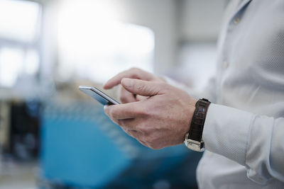 Close-up of businessman using cell phone in a factory