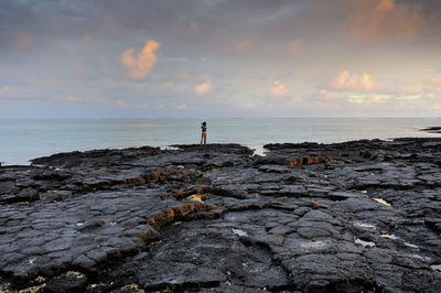 Silhouette man standing on beach against sky during sunset