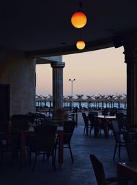 Empty chairs and tables in restaurant against sky