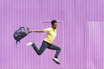 Side view of man jumping on pink umbrella