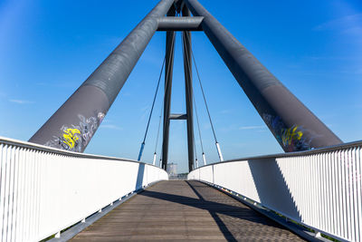 Low angle view of footbridge against clear blue sky