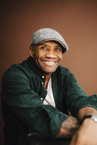 Portrait of happy mature man against brown background