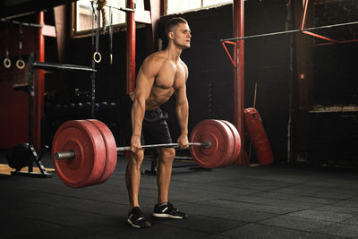 Full length of shirtless man working out at gym