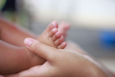 Cropped hands of mother holding baby legs