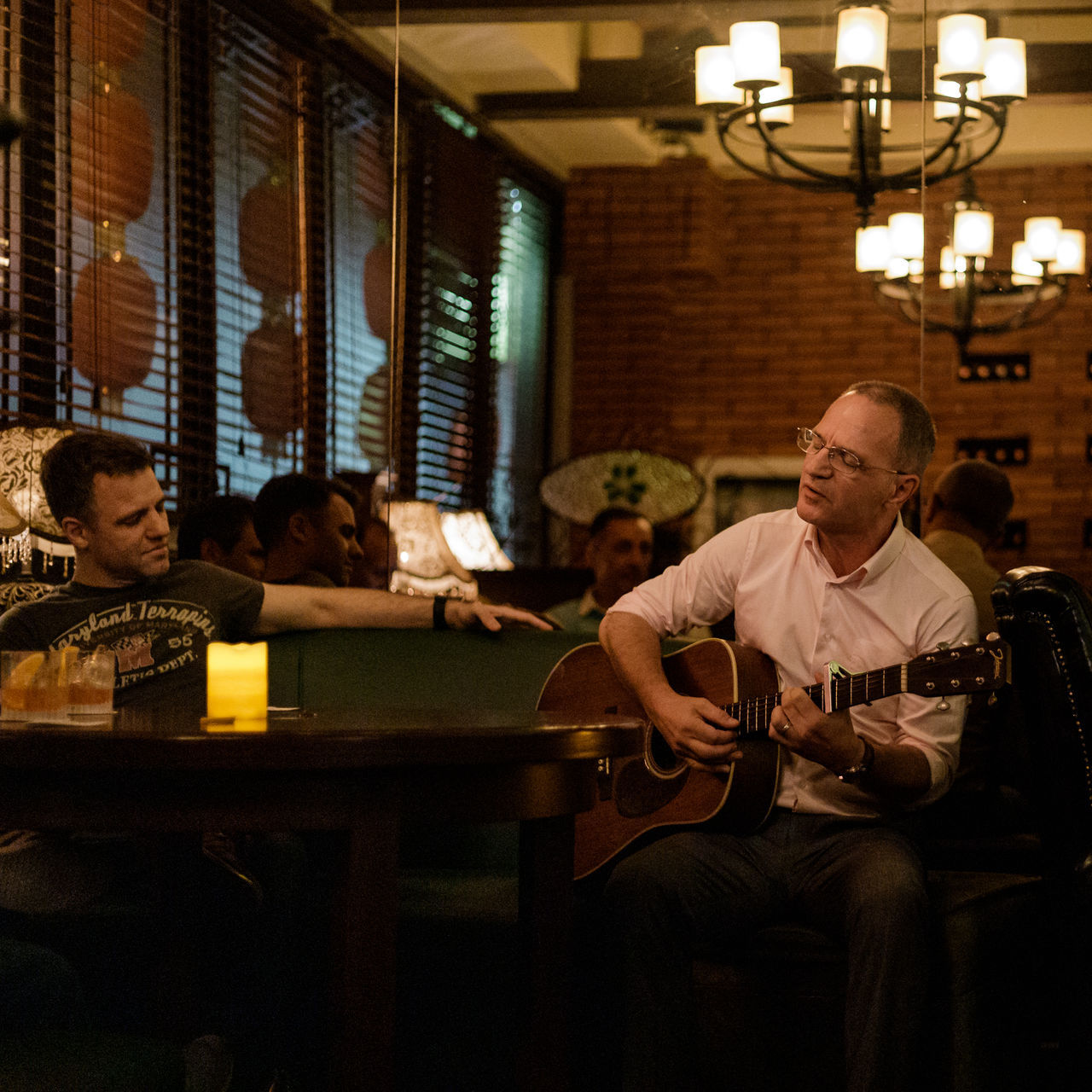 sitting, musical instrument, string instrument, indoors, real people, music, men, playing, mature men, males, guitar, adult, leisure activity, arts culture and entertainment, mature adult, people, incidental people, senior adult, musical equipment, plucking an instrument