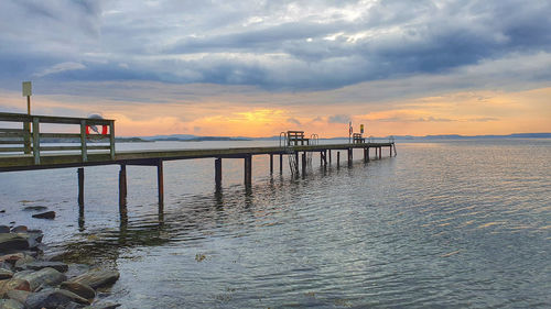Pier over sea against sky during sunset