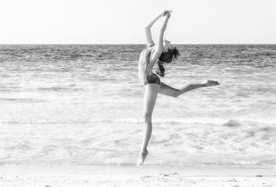 Full length of woman doing ballet dance at beach