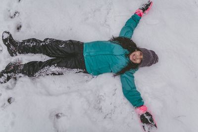 Directly above shot of girl lying down on snow