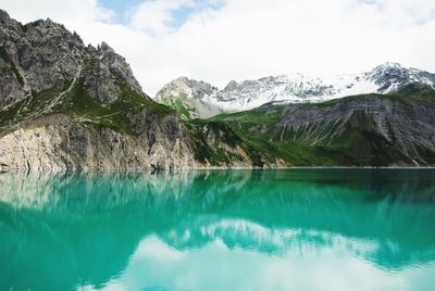 Scenic view of lake by mountains against sky