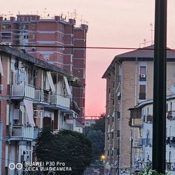 Buildings in city against sky during sunset