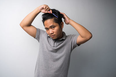 Portrait of young man standing against white background