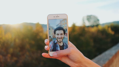 Cropped hand of woman video calling on phone outdoors