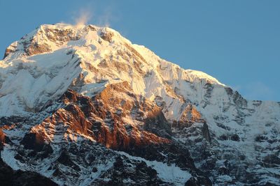 Sunlight on snowcapped mountain range against clear sky