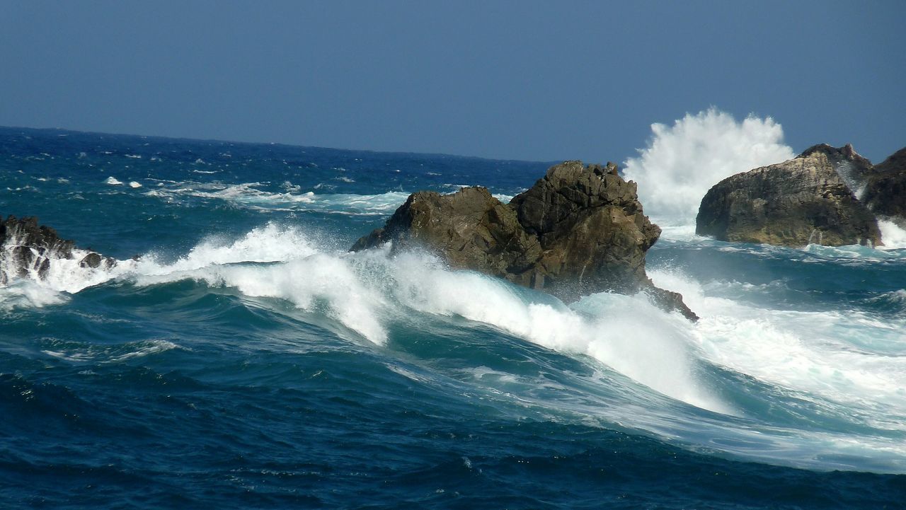 sea, water, scenics, beauty in nature, surf, wave, nature, blue, horizon over water, motion, tranquil scene, tranquility, sky, rock - object, rock formation, power in nature, clear sky, splashing, idyllic, waterfront