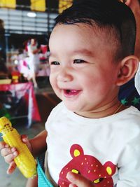 Cute baby boy looking away holding corn