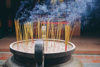 Close-up of incense sticks burning in container at temple