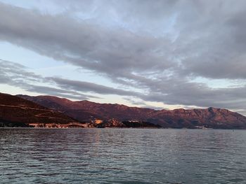 Scenic view of sea by mountains against sky