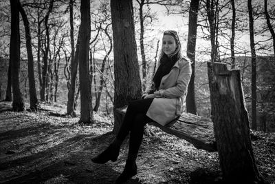 Man sitting by tree trunk in forest