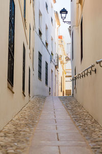 Narrow cobbled street, with a metal railing on the wall.