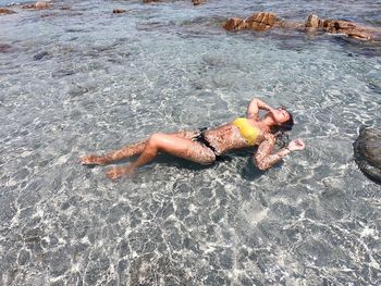 High angle view of woman wearing bikini relaxing in sea