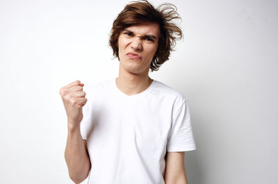 Portrait of young man standing against white background